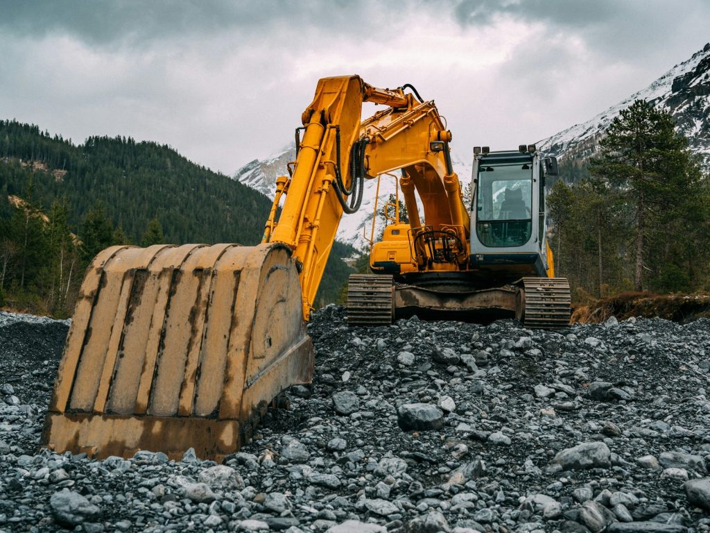 Yellow excavator on a gravel riverbed in the mountains