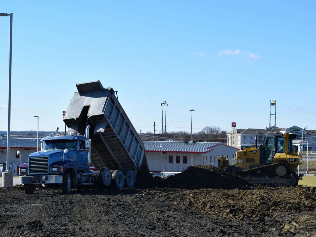 Dump truck unloading dirt next to a bulldozer